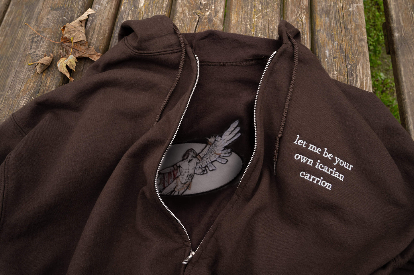 Flat lay of Hozier I, Carrion inspired hoodie, featuring silver full-zip hardware, drawstring hood, ribbed cuffs and hem, kangaroo pouch pockets and white thread lyric embroidery.