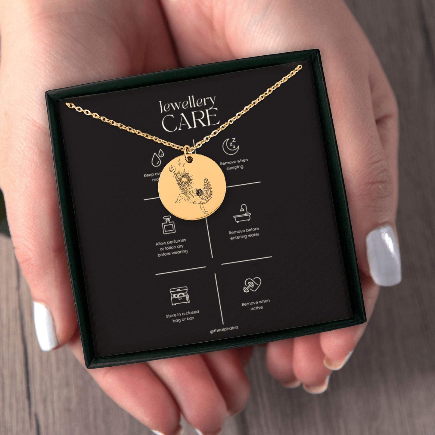 A gold round pendant with a cable chain and lobster clasp engraved with Icarus falling, inspired by Hozier's 'Sunlight' from Wasteland, Baby!, displayed in the packaging.