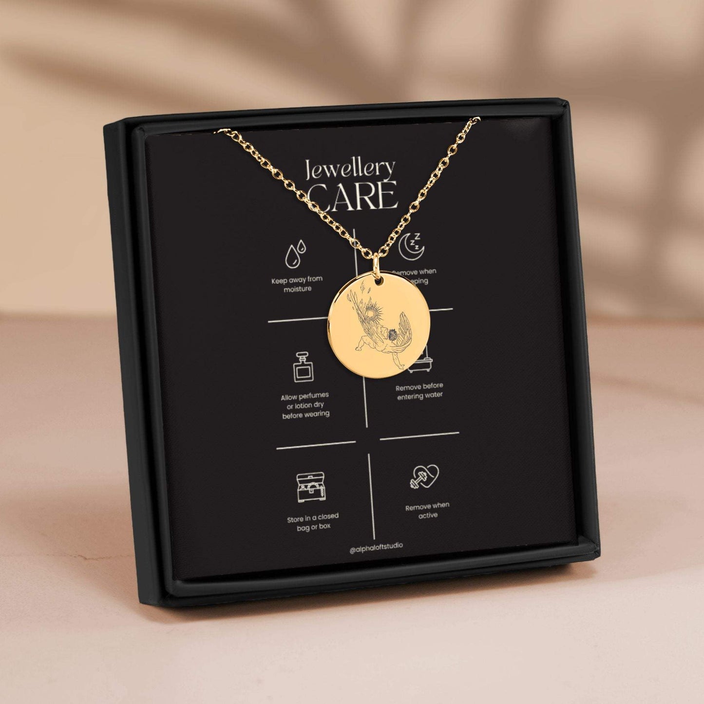 Gold Icarus mythology necklace in packaging showing engraved design