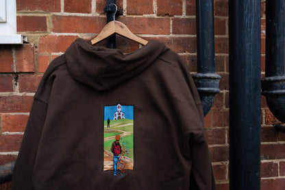 Back view of brown fleece-lined zip-up hoodie on a hanger, large vertical embroidery of a figure walking toward a church with stained glass fragments scattering -Noah Kahan The Great Divide inspired, embroidered zip-up hoodie

