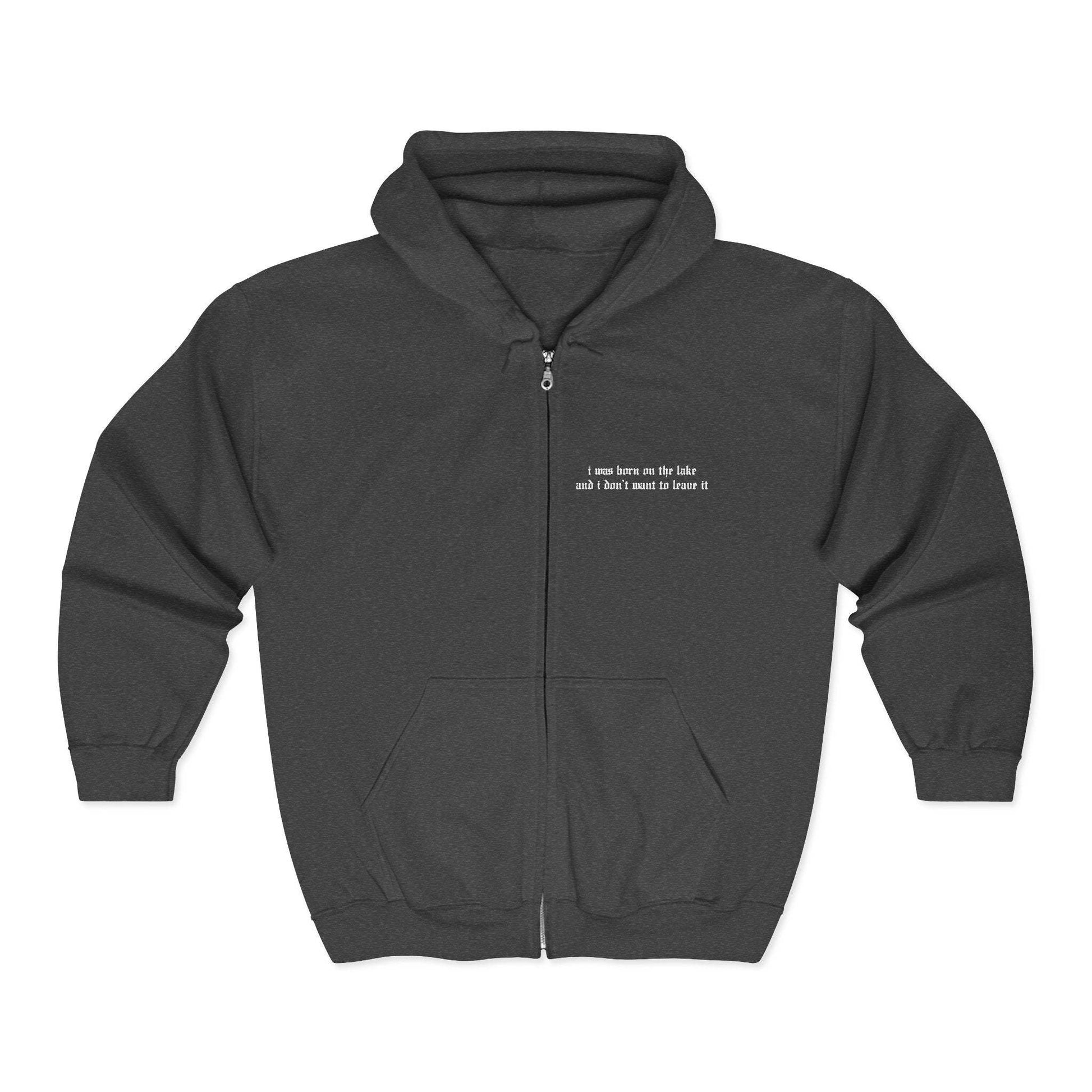 Charcoal zip-up hoodie mockup, silver metal full-zip closure, drawstring hood, kangaroo pocket, small left-chest old-English lyric embroidery "i was born on the lake and i don't want to leave it" - Lord Huron Ghost on the Shore inspired hoodie

