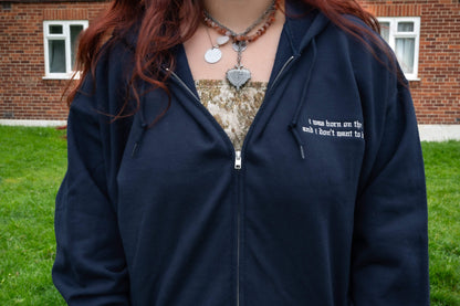 Navy full-zip fleece hoodie worn outdoors, silver metal zipper, drawstring hood, small left-chest old-English lyric embroidery reading "i was born on the lake and i don't want to leave it" - Lord Huron Ghost on the Shore inspired embroidered hoodie